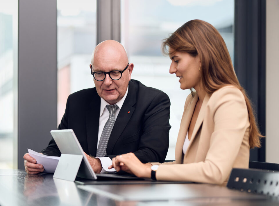 Zwei Anwälte der Kanzlei Kessler Landolt Giacomini & Partner besprechen Dokumente am Tablet in der modernen Kanzlei in Schwyz